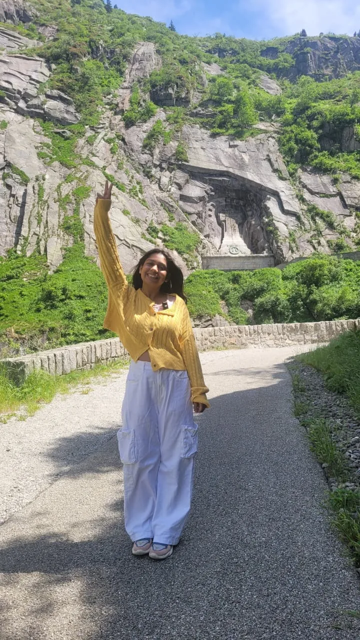Traveler Jyoti on the Schöllenen Gorge walking path with the cliff wall behind