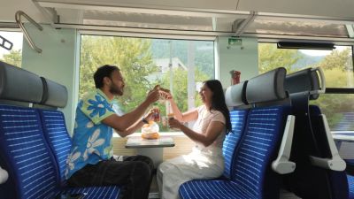 Traveler Jyoti and a friend sharing a snack at a table inside a Swiss regional train