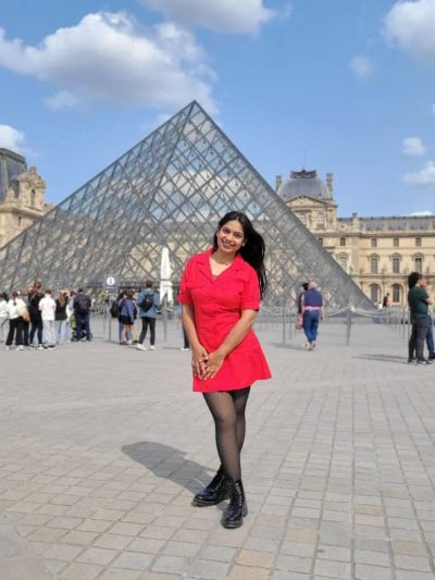 Traveler Jyoti in front of the glass pyramid at the Louvre in Paris