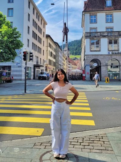 Traveler Jyoti on a crosswalk in the old town of Chur, Switzerland's oldest city, with historic buildings behind