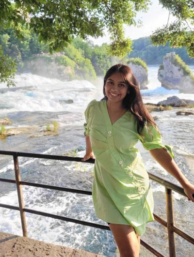 Traveler Jyoti close to the Rhine Falls with the famous mid-river rock visible behind, the same rock the Felsenfahrt boat drops passengers at