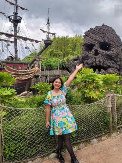 Traveler Jyoti in front of a pirate ship and Skull Rock in Adventureland, Disneyland Paris
