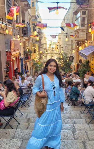 Traveler Jyoti smiling on a lantern-lit street in Valletta, Malta