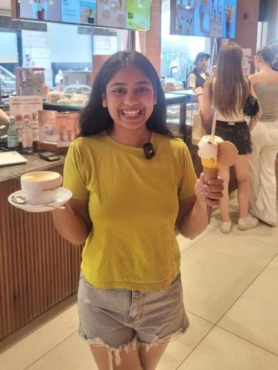 Traveler Jyoti holding a cappuccino and a gelato cone at Cioccolatitaliani in Milan