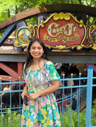 Traveler Jyoti in front of the Casey Jr circus train ride sign in Fantasyland, Disneyland Paris