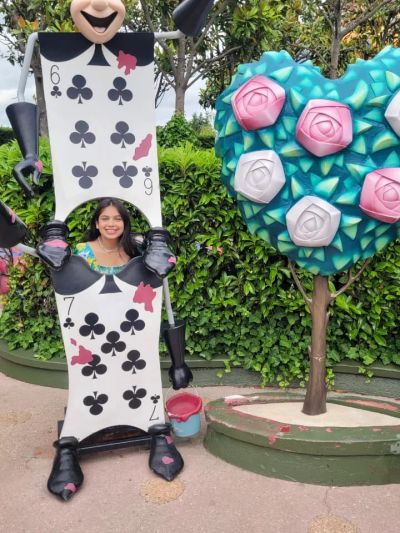 Traveler Jyoti peeking through a playing-card soldier cutout at Alice's Curious Labyrinth, Disneyland Paris