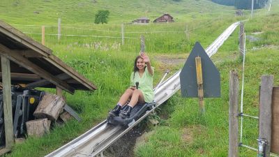 Traveler Jyoti sitting in the toboggan sled on the Fräkigaudi summer toboggan run at Fräkmüntegg on Mount Pilatus