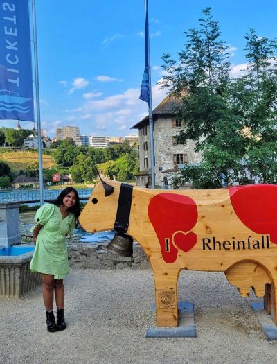 Traveler Jyoti with the I Heart Rheinfall wooden cow statue near the Rhine Falls boat ticket area in Neuhausen