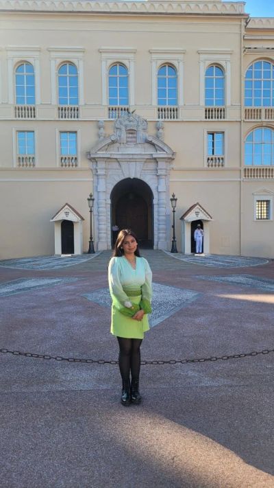 Traveler Jyoti in front of the Prince's Palace of Monaco, with a Carabinier guard on duty at the entrance