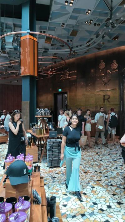 Traveler Jyoti inside the Starbucks Reserve Roastery in Milan with the mosaic floor and roasting hall behind her