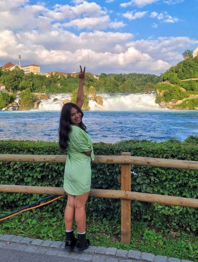Traveler Jyoti at the Rhine Falls overlook on the free Neuhausen side, peace sign, full panoramic view of the falls behind
