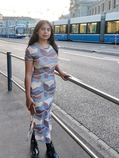 Traveler Jyoti beside the blue Zurich tram outside the main station on her last day in Switzerland